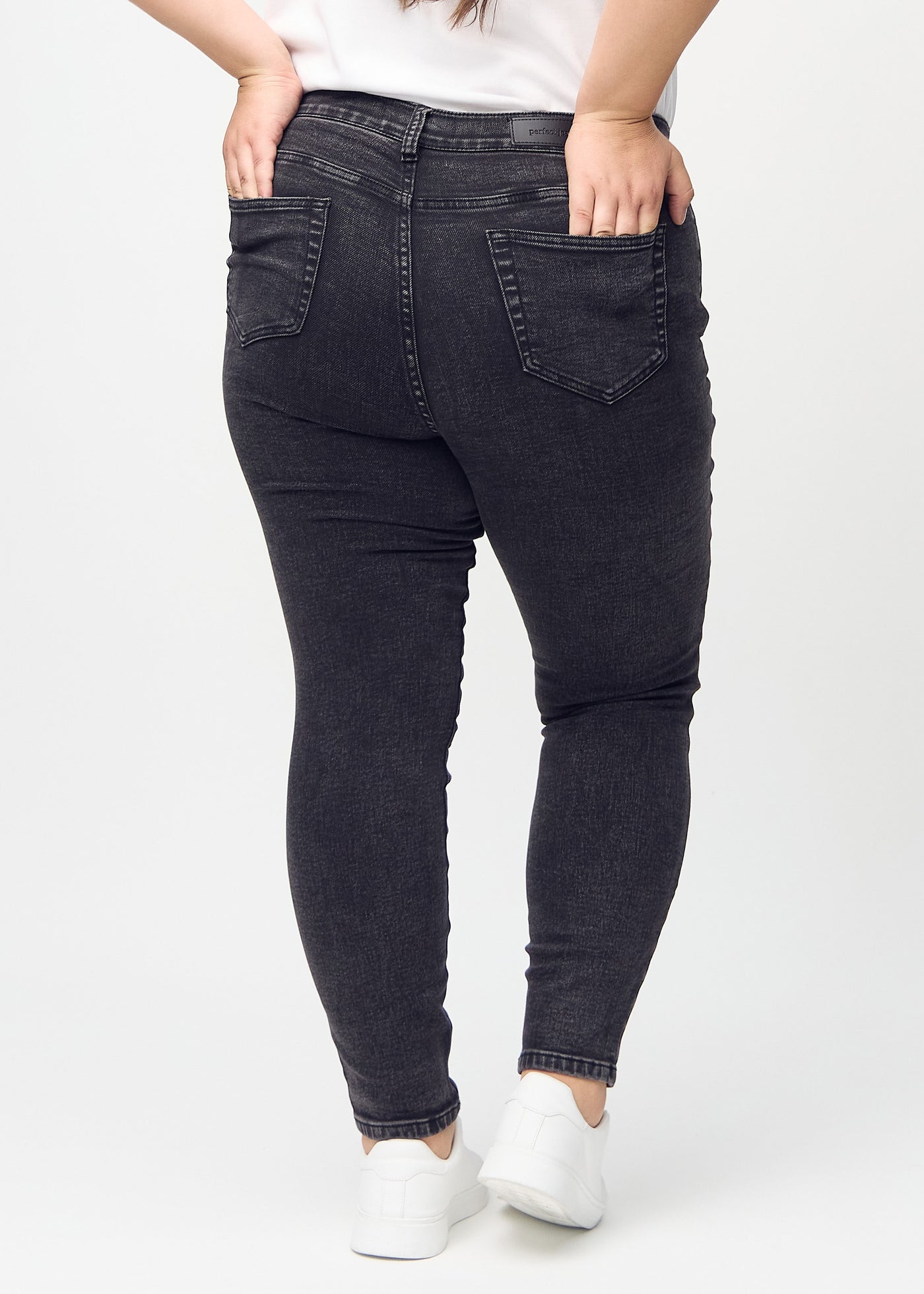 Mørkegrå denim skinny jeans set bagfra på en plus-size model, så man kan se hele produktet.