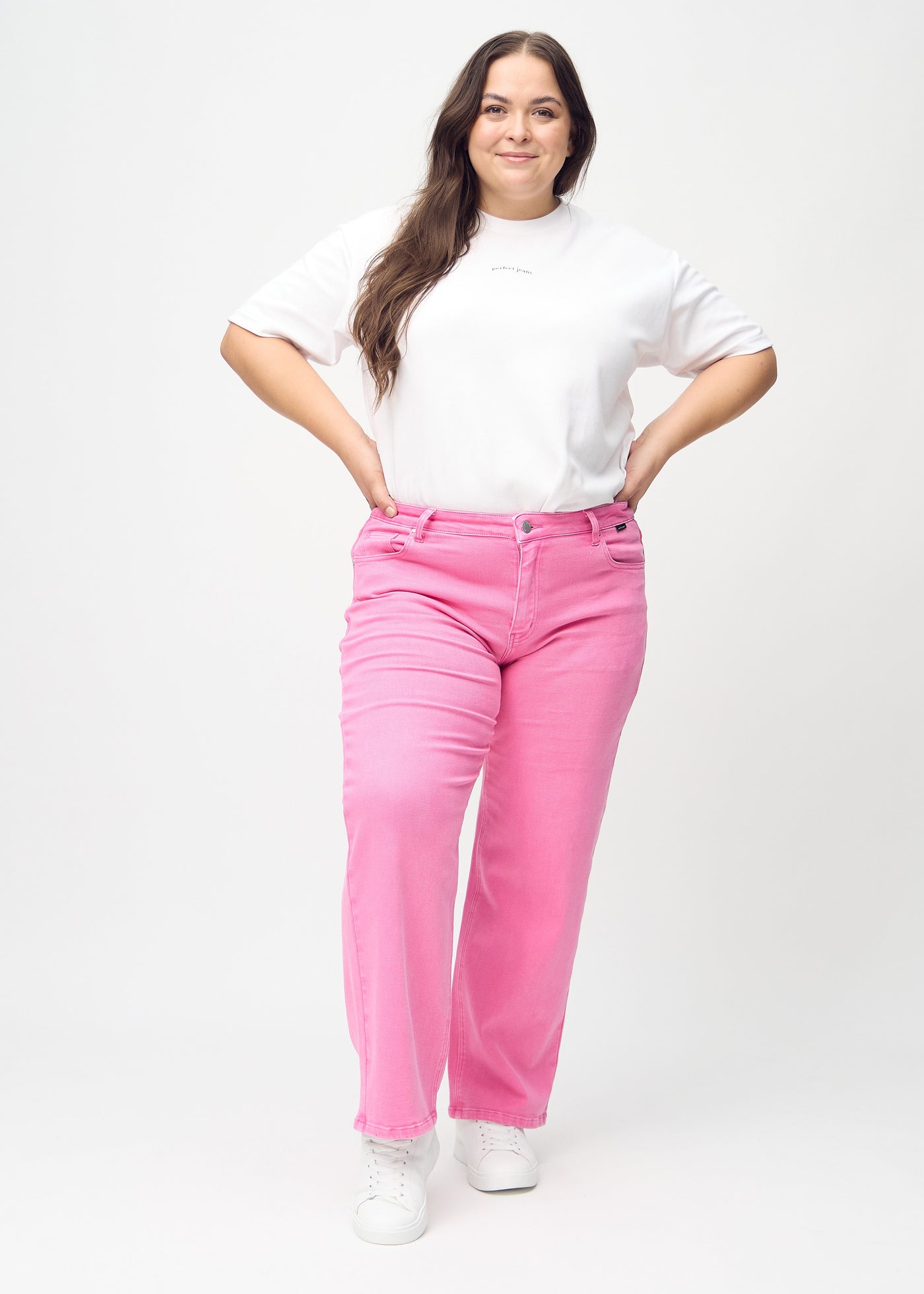 Fuldt billede af en plus-size model i lyserøde loose jeans.