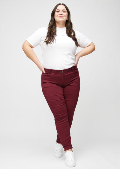 Fuldt billede af en plus-size model i mørkerøde slim jeans.