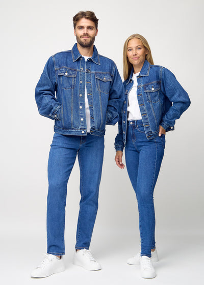 Fuldt billede af unisex mørkeblå denim jakke, set forfra på herre og dame model, hvor man ser knapper og lommer i farven Oceans.