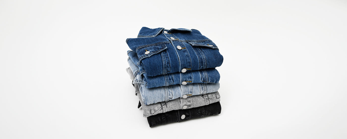 Fem forskellige farver af denimjakker fra Perfect Jeans foldet sammen i en stak