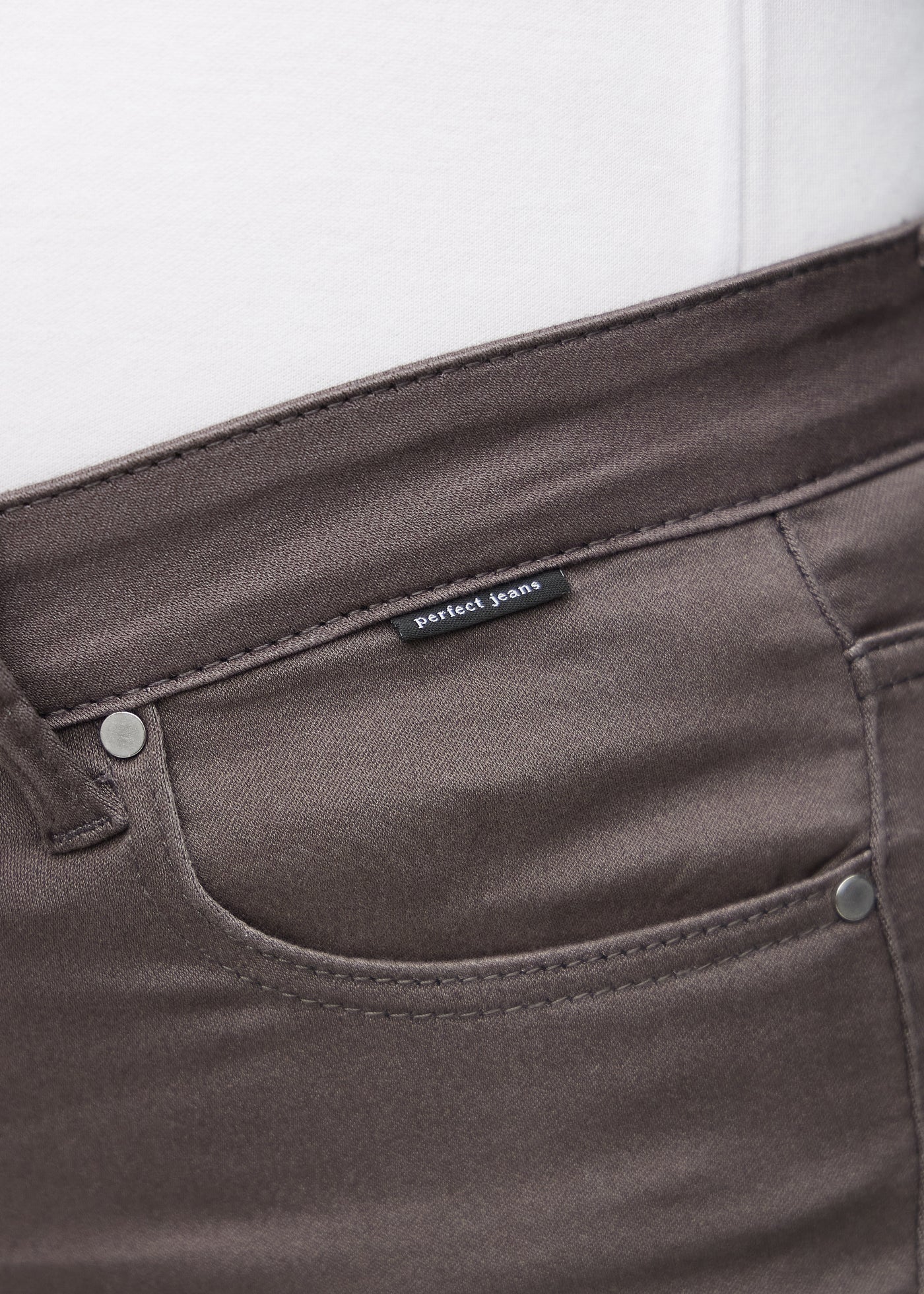 Forlommen på et par gråbrune jeans, hvor man kan se logoet på en plus-size model.