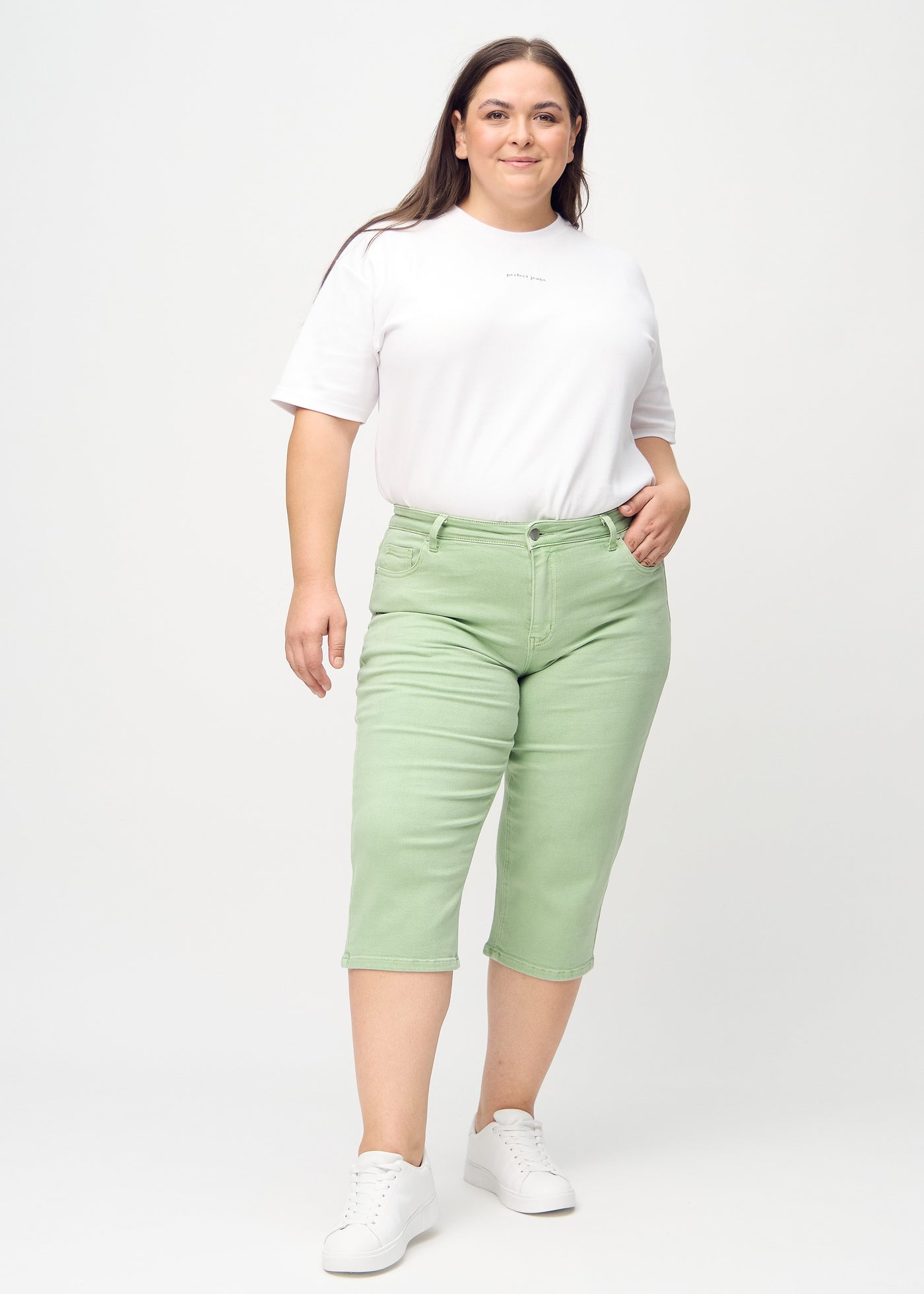 Plus-size model går ind i billedet, strækker i sine capris, viser dem frem ved at dreje rundt, og forlader derefter billedet.